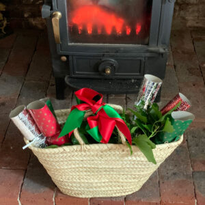 Little rope handle basket filled with Christmas crackers, ivy and ribbons