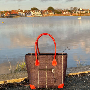 Vero raffia handbag in black pinstripes beside a pond