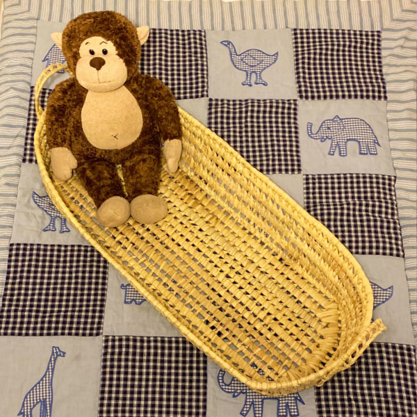 Baby changer woven basket with toy on children's quilt
