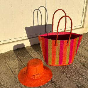 Bato bag in multi colour stripes with a raffia hat at a beach hut