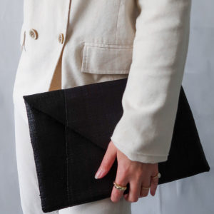 Black envelope clutch bag held by model