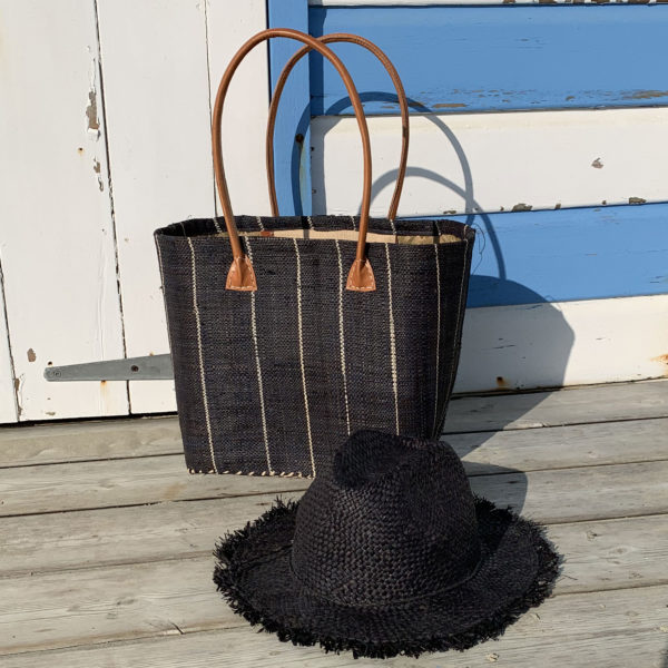 Black frayed Fedora hat with small black pinstripe basket by beach hut