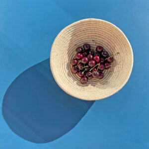 Natural raffia fruit bowl filled with cherries