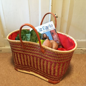 Large red drawstring shopper basket with vegetables and a magazine