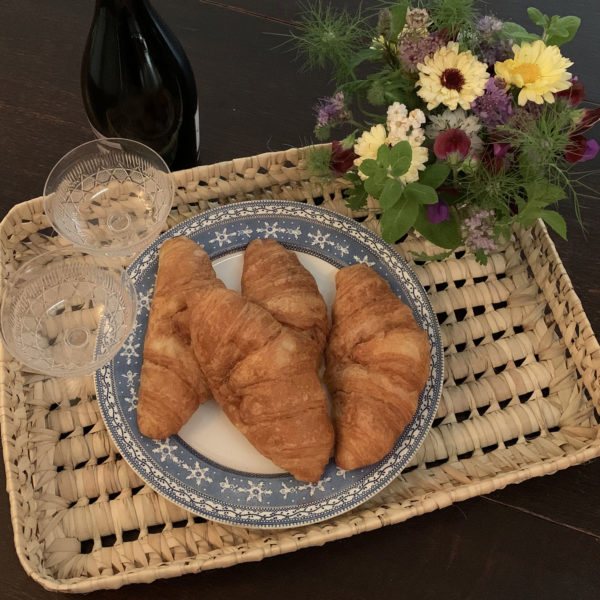 Large flat tray with croissants, champagne glasses and a posy of flowers for a breakfast celebration