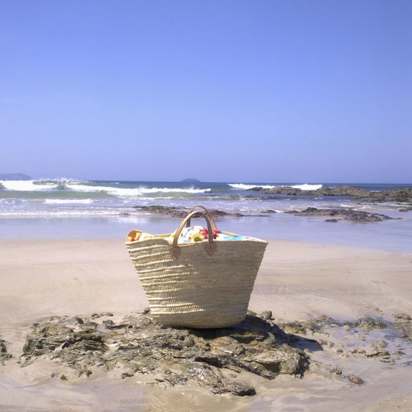 Large French basket filled with towels at beach