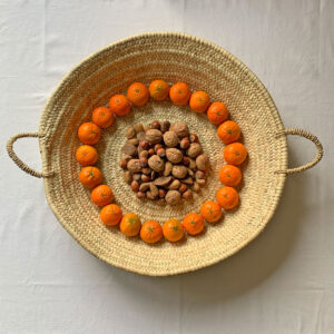 Large round palm tray filled with nuts and satsumas at Christmas time