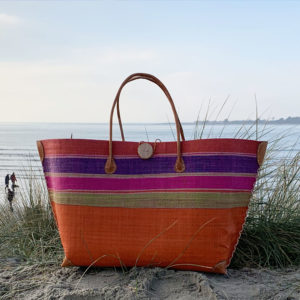 Orange mery button beach basket with stripes at seaside