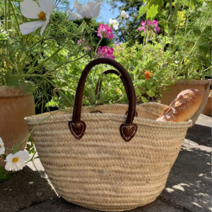 Round handle basket with bread beside flowers