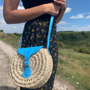 Blue round palm handbag being worn across the body