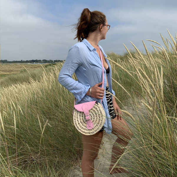 Pink round palm handbag being worn across the body