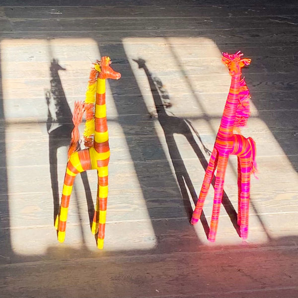 Small raffia giraffes in sunny window shadow