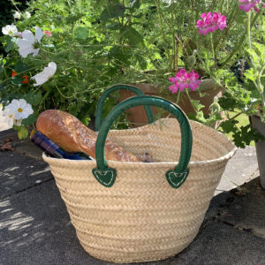 Small green handle French market basket with bread beside flowers