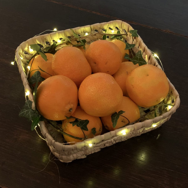 Small square woven tray with fairy lights and satsumas