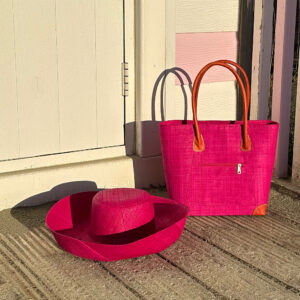 Vero Handbag and Mimosa Hat in pink by a beach hut