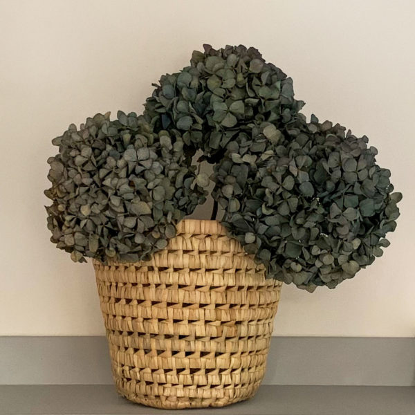 Woven palm waste paper basket filled with dried hydrangeas