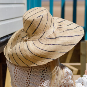 Large mimosa hat in natural pinstripe modelled by the sea