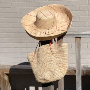 Natural and pink pinstripe hat with a natural crochet drawstring bag in a garden