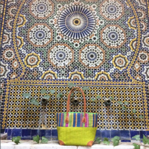 Large Hanta Stripe Bag in lime green and stripes beside Moroccan tiled fountain