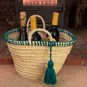 Little green wool tassel basket with wine and champagne as a Christmas gift hamper