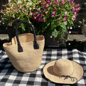 Black handle and natural crochet bucket bag with black rim crochet hat on a picnic rug