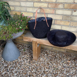 Black Crochet Drawstring Bag with black Mimosa Hat on a garden bench