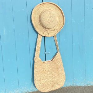 Boho Crossbody Bag with matching crochet raffia hat hanging at a beach hut
