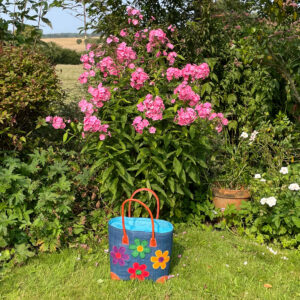 Medium turquoise flowers tote bag in a garden