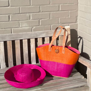 Raffia button bag in orange and pink with pink mimosa hat on a bench