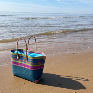 Mery drawstring basket in blue on a beach beside the sea