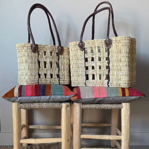 Small and medium woven reed baskets on top of rustic wooden stools