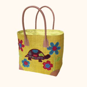 Medium size tote bag with embroidered tortoise and flowers on one side with a lemon background cut out photo
