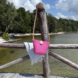 PlusPlus Handbag in pink hanging on post by lake in Madagascar
