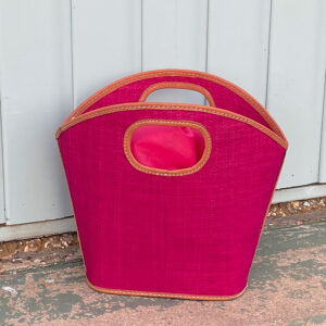Toky raffia handbag in pink beside a beach hut