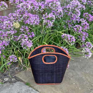 Toky Handbag in black beside a flower bed