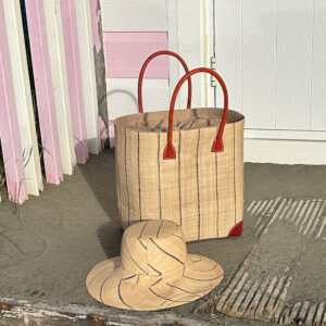 Amelie natural pinstripe hat with large Hanta pinstripe tote bag beside a beach hut