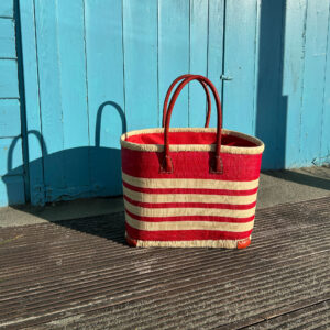 Medium red and natural Porto Basket Bag beside a beach hut