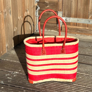 Small Porto Basket Bag in red and natural beside a wooden beach hut