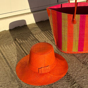 Orange Amelie raffia sun hat with bright stripe Bato Basket Bag at beach