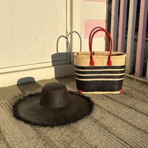 Small porto stripe raffia bag and frayed raffia sun hat in black at beach