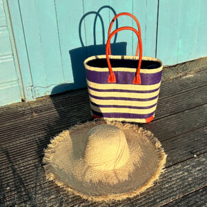 Small navy porto stripe raffia bag with natural frayed raffia sun hat at the beach