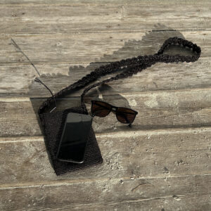 Crochet phone bag in black raffia with sunglasses and an iphone